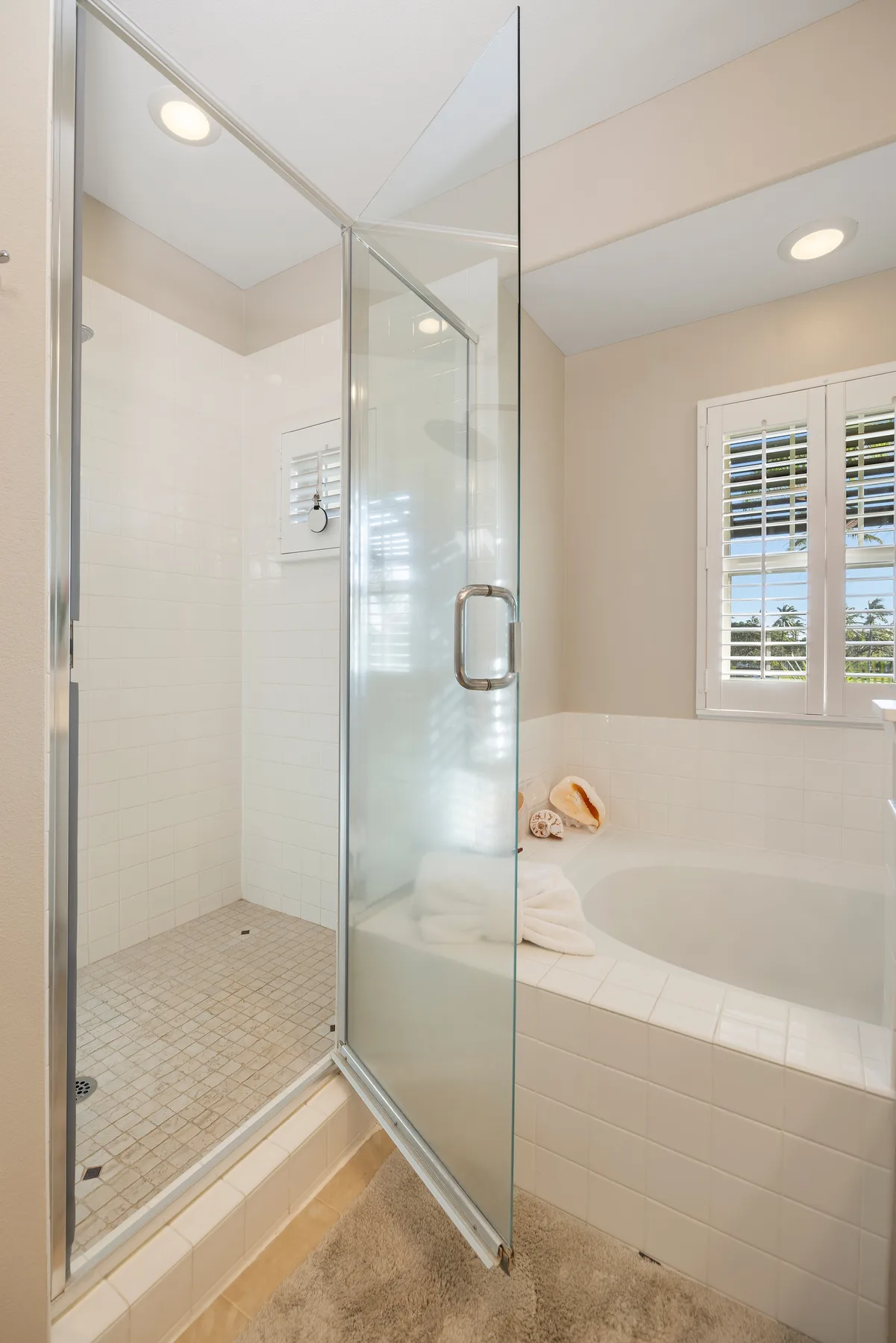 Un baño con una ducha de vidrio y una bañera junto a una ventana.
