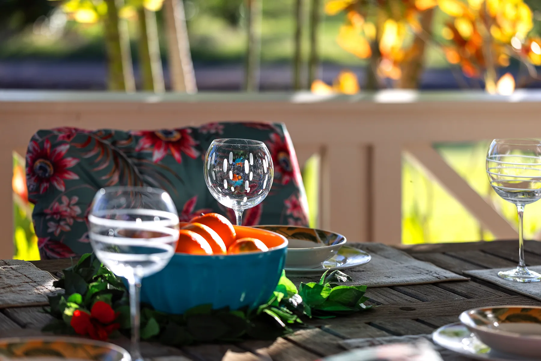 Una mesa preparada con cuencos, vasos y verduras frescas en un patio al aire libre.