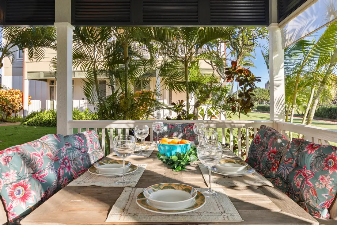 Un comedor exterior cubierto con una mesa puesta y plantas tropicales.