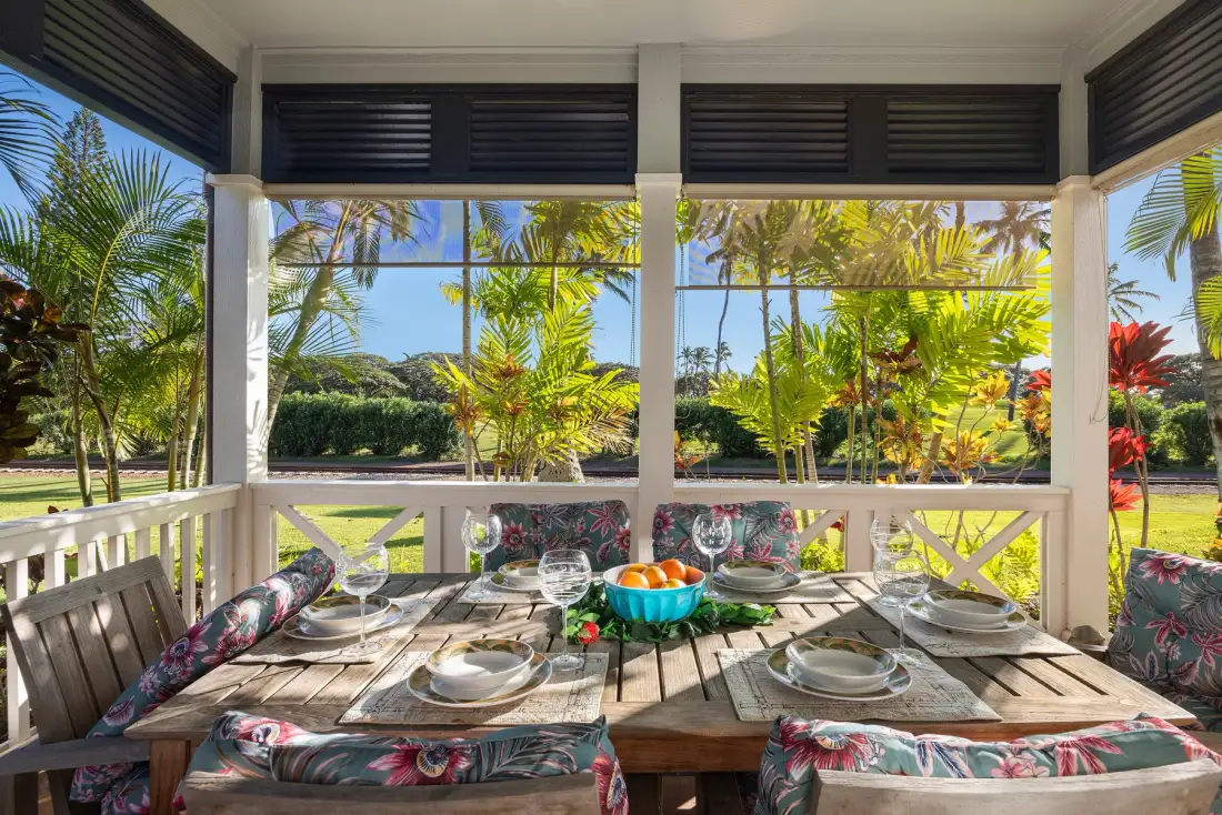 Un comedor al aire libre con la mesa puesta da a un exuberante jardín tropical.