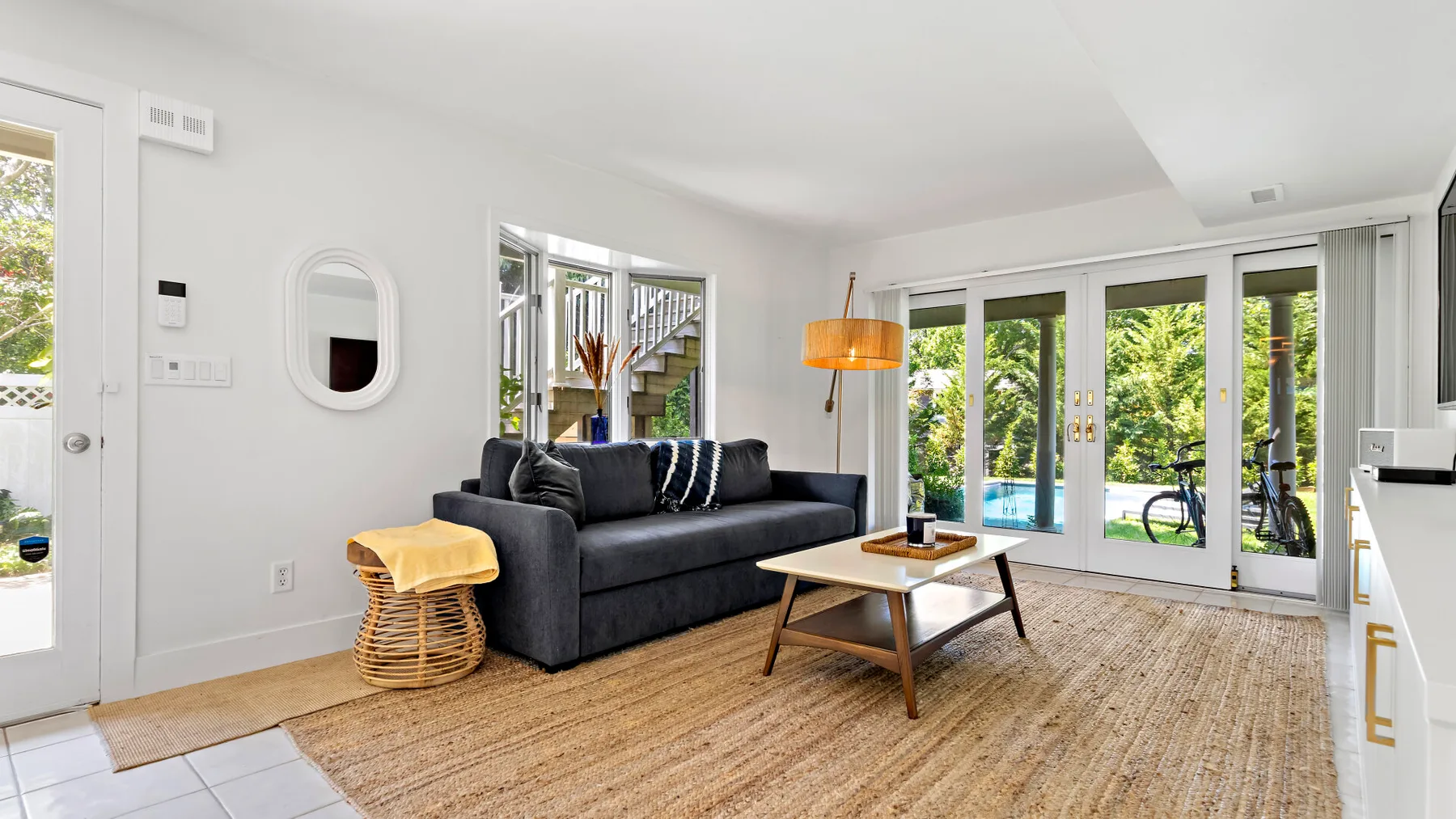 A bright living room with a dark sofa and glass doors opening to a patio.