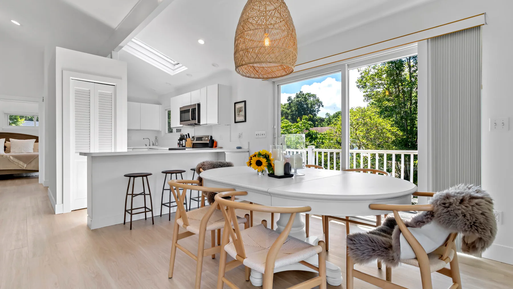 A bright open-plan kitchen and dining area with a large table beside a balcony.