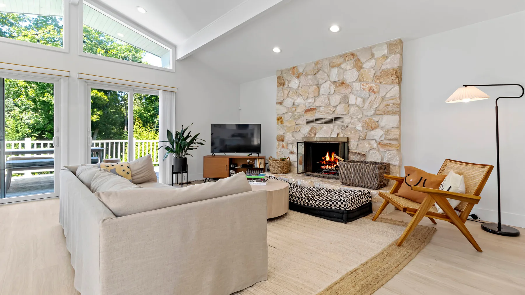 A bright living room with a fireplace, seating, and large windows.