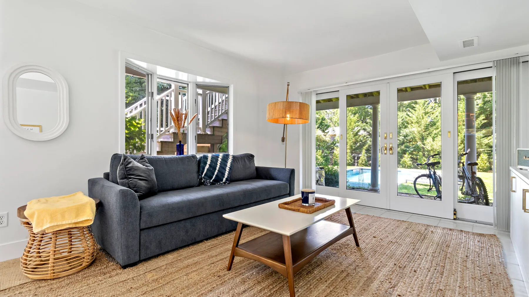 A bright living room with dark seating, a coffee table, and glass doors opening to a patio.