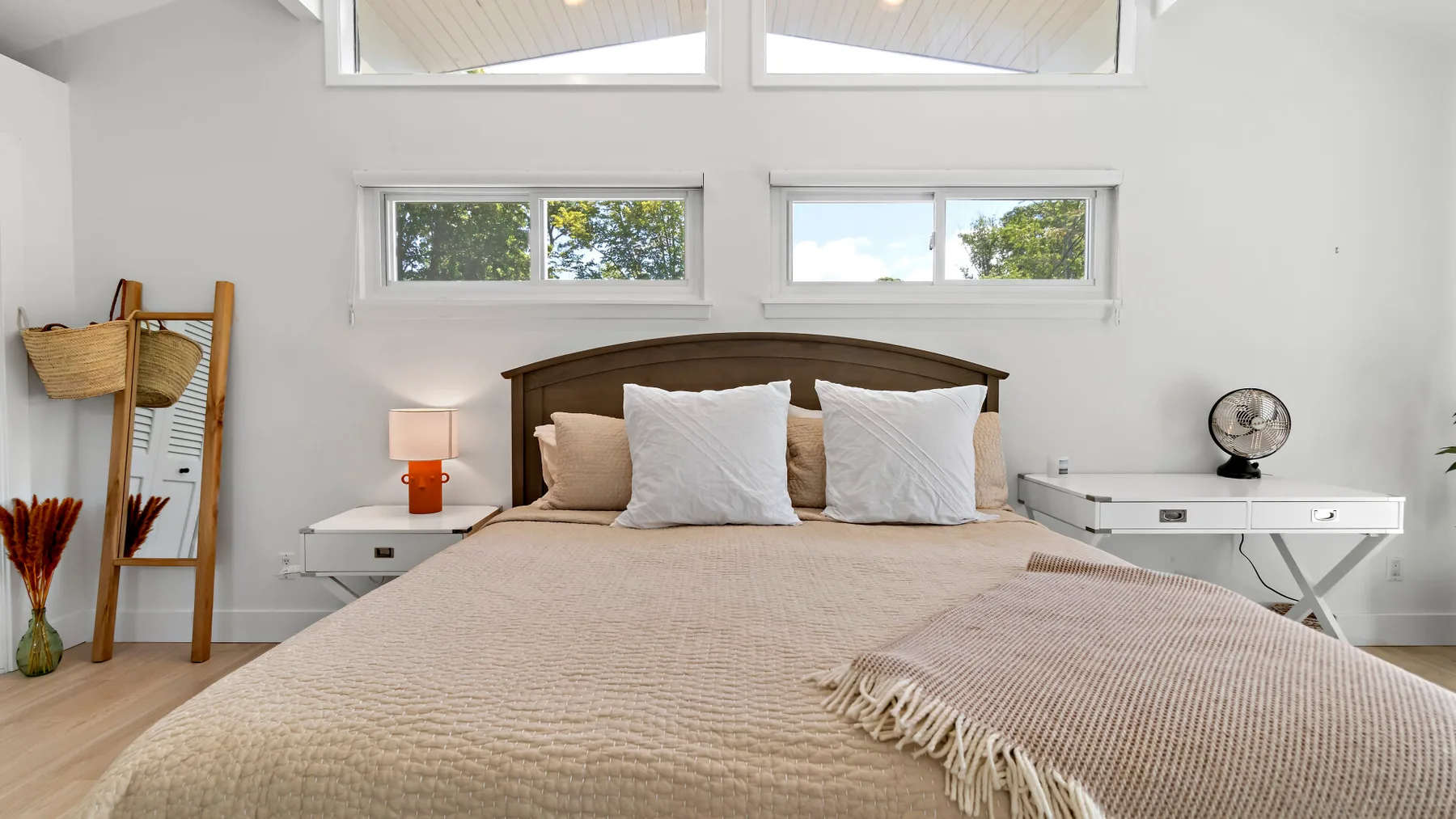A bright bedroom with a bed beneath several wide windows.
