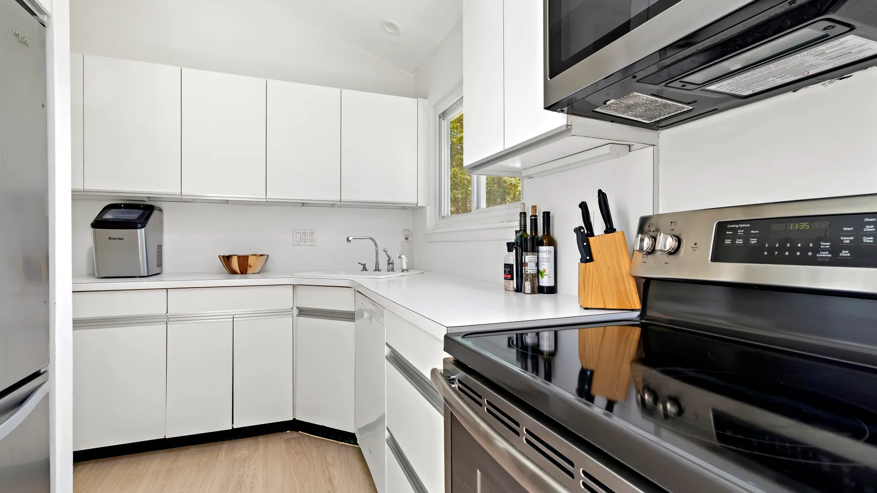 A bright modern kitchen with white cabinets and stainless steel appliances.