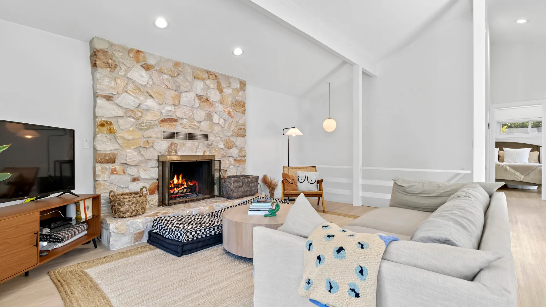 A bright living room with a stone fireplace and seating around a coffee table.