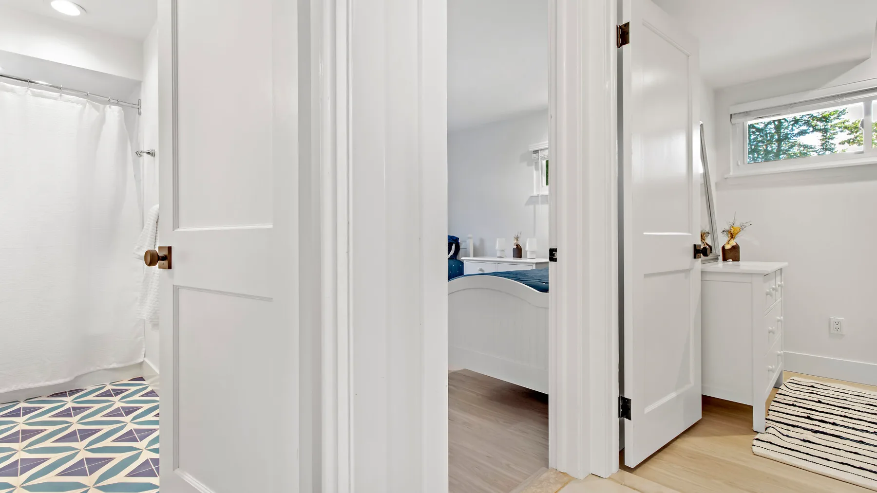 A bathroom with a shower, vanity, and a small high window.