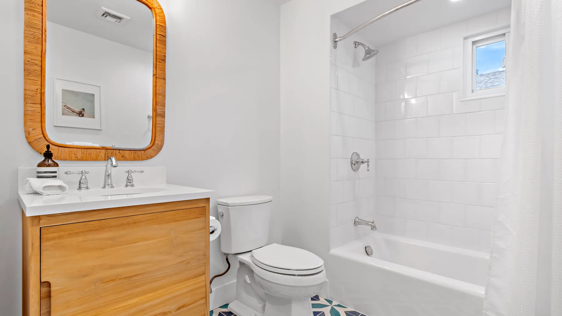 A bright bathroom with a wood vanity and a tiled bathtub and shower.