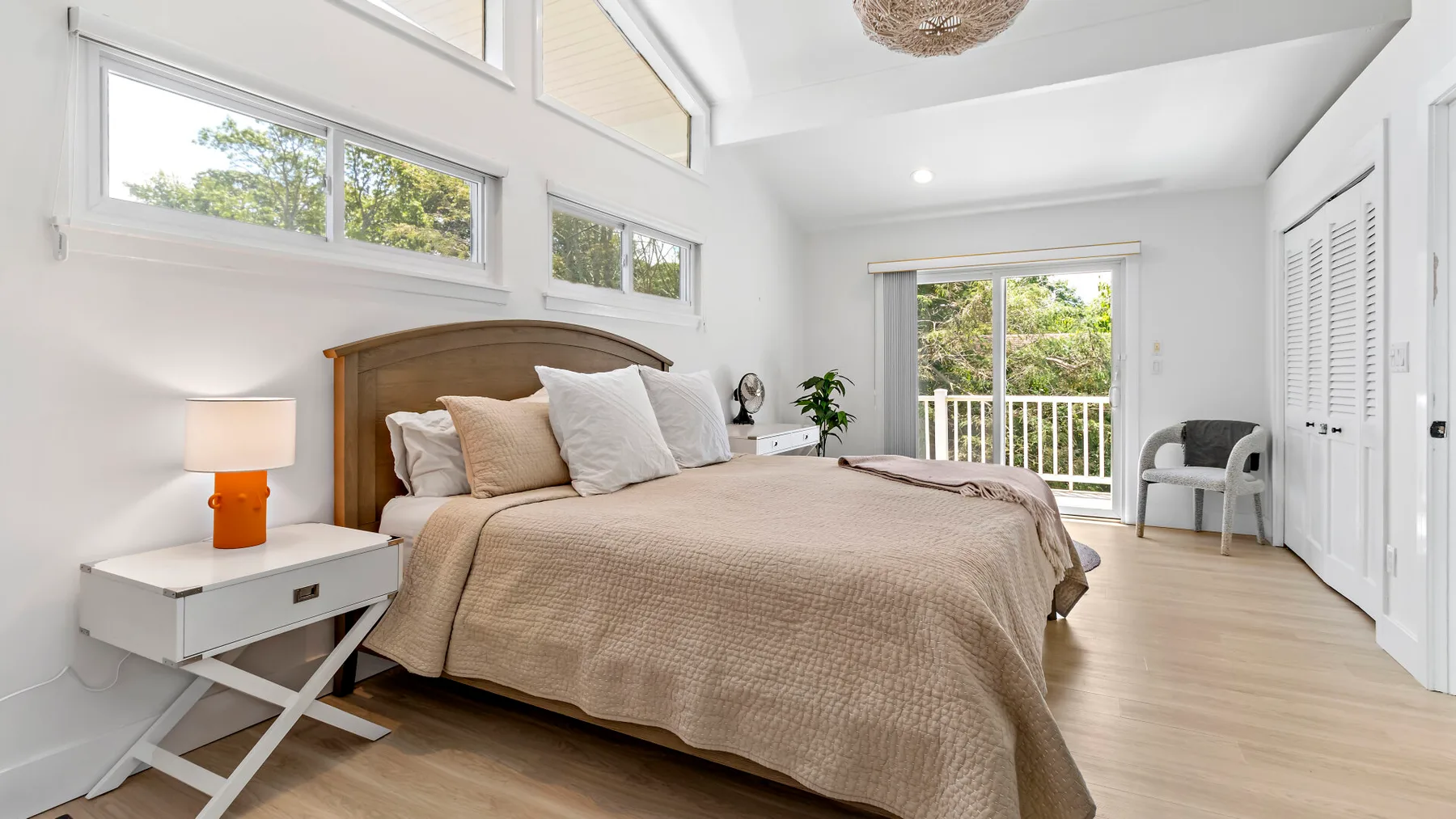 A bright bedroom with a large bed, high windows, and a balcony door.