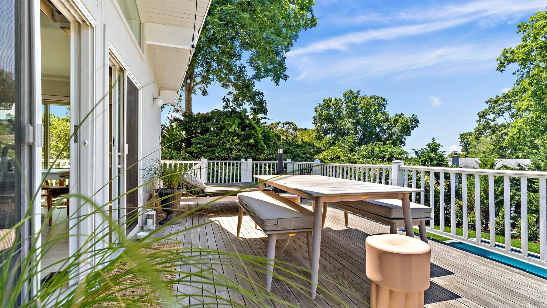 An outdoor deck with a dining table and seating beside a white railing.