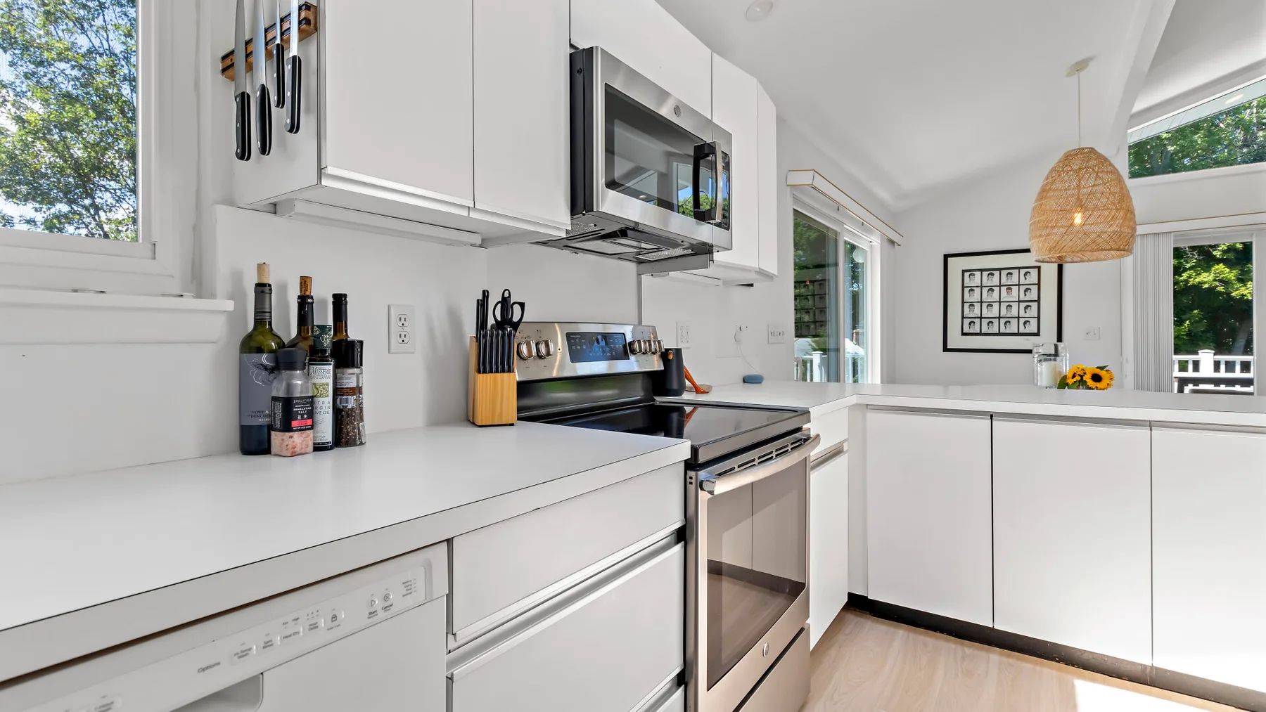 A bright kitchen with white cabinets, a stove, and a microwave.