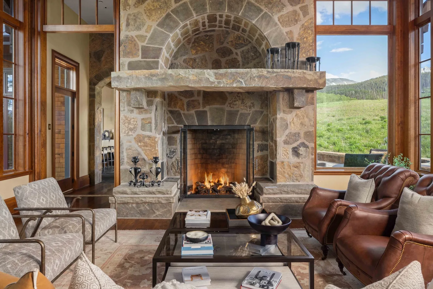 A living room with a large stone fireplace and seating arranged around a coffee table.