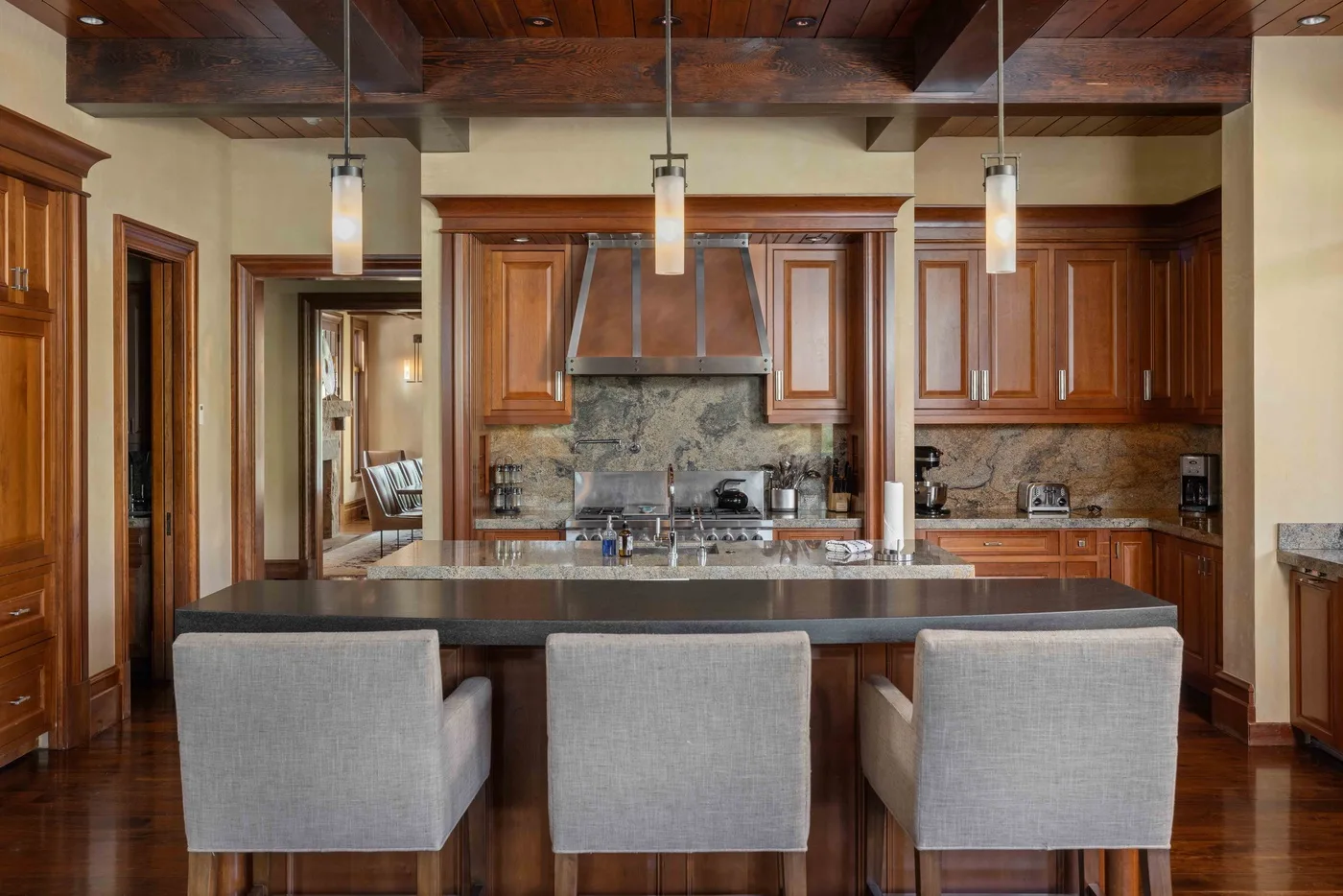 A spacious kitchen features a central island with seating and wooden cabinetry.