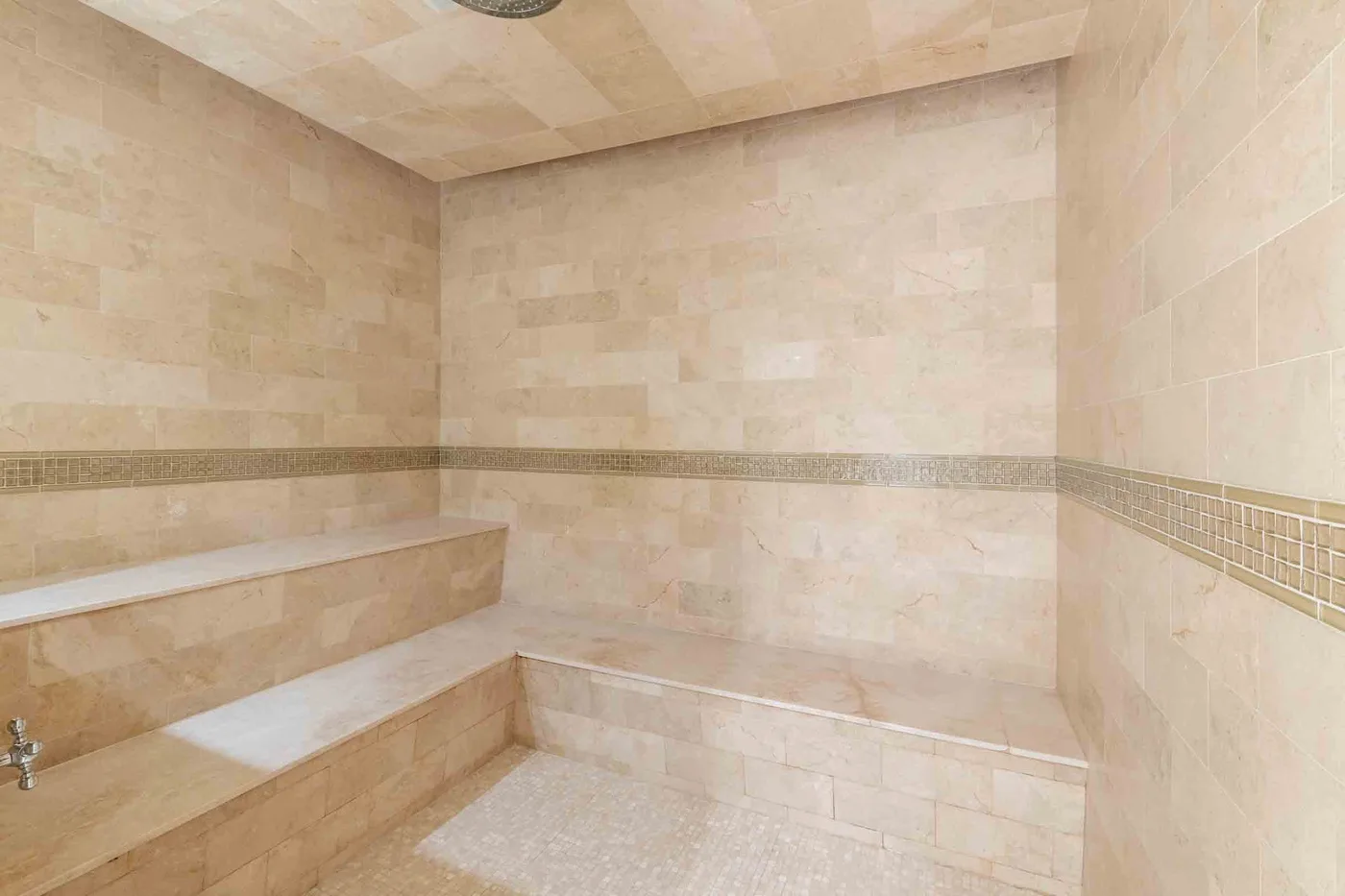 A tiled bathroom with a built-in bench and decorative horizontal wall trim.