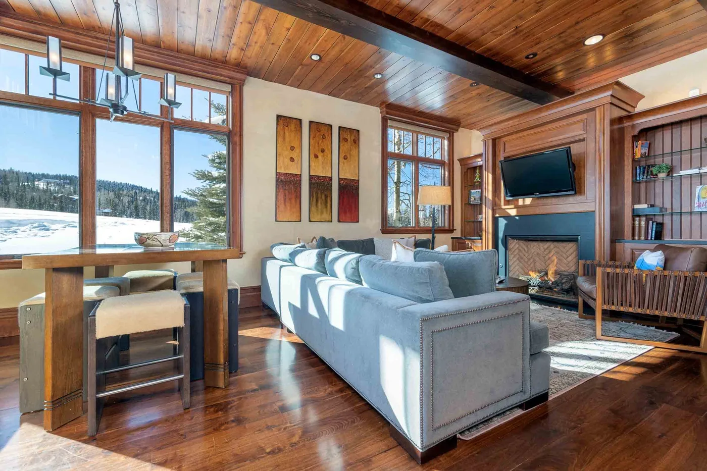 A living room with a sofa, dining table, and fireplace beside large windows.