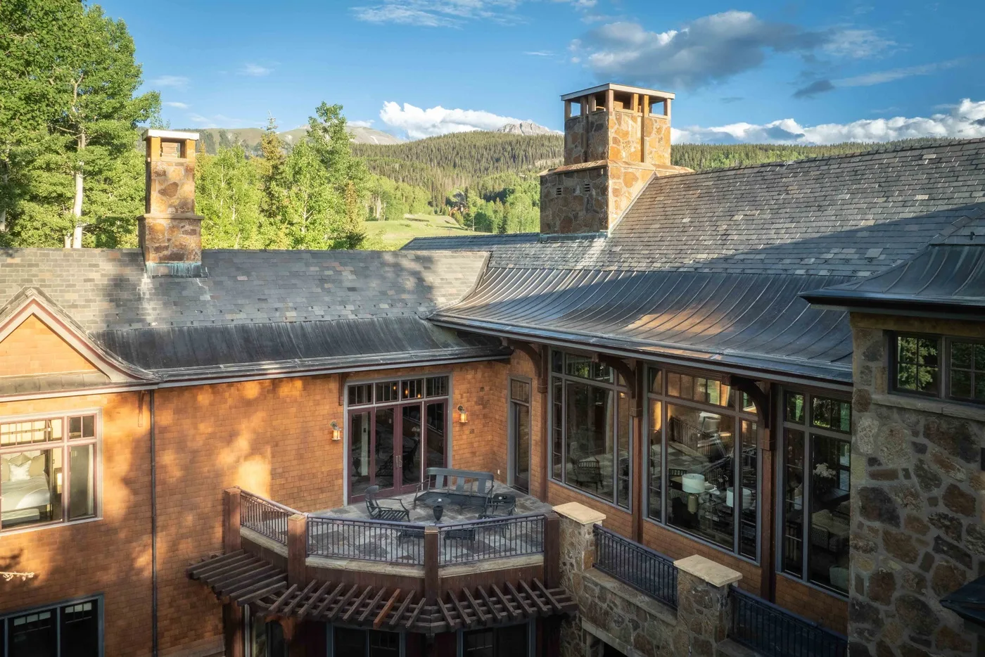 A stone-and-brick building with a wooden deck, surrounded by green hills.