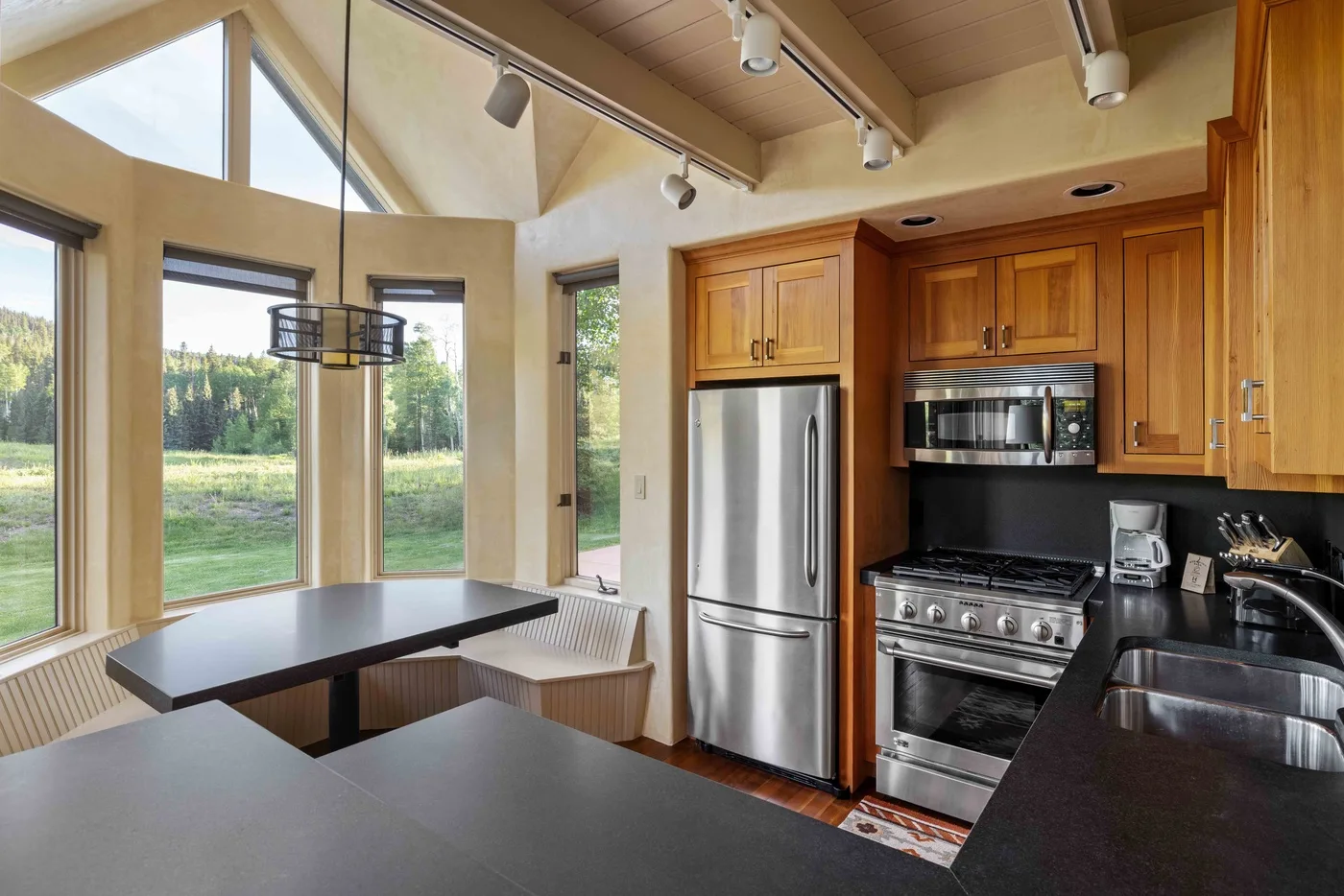 A bright kitchen with wood cabinetry, stainless steel appliances, and large windows.