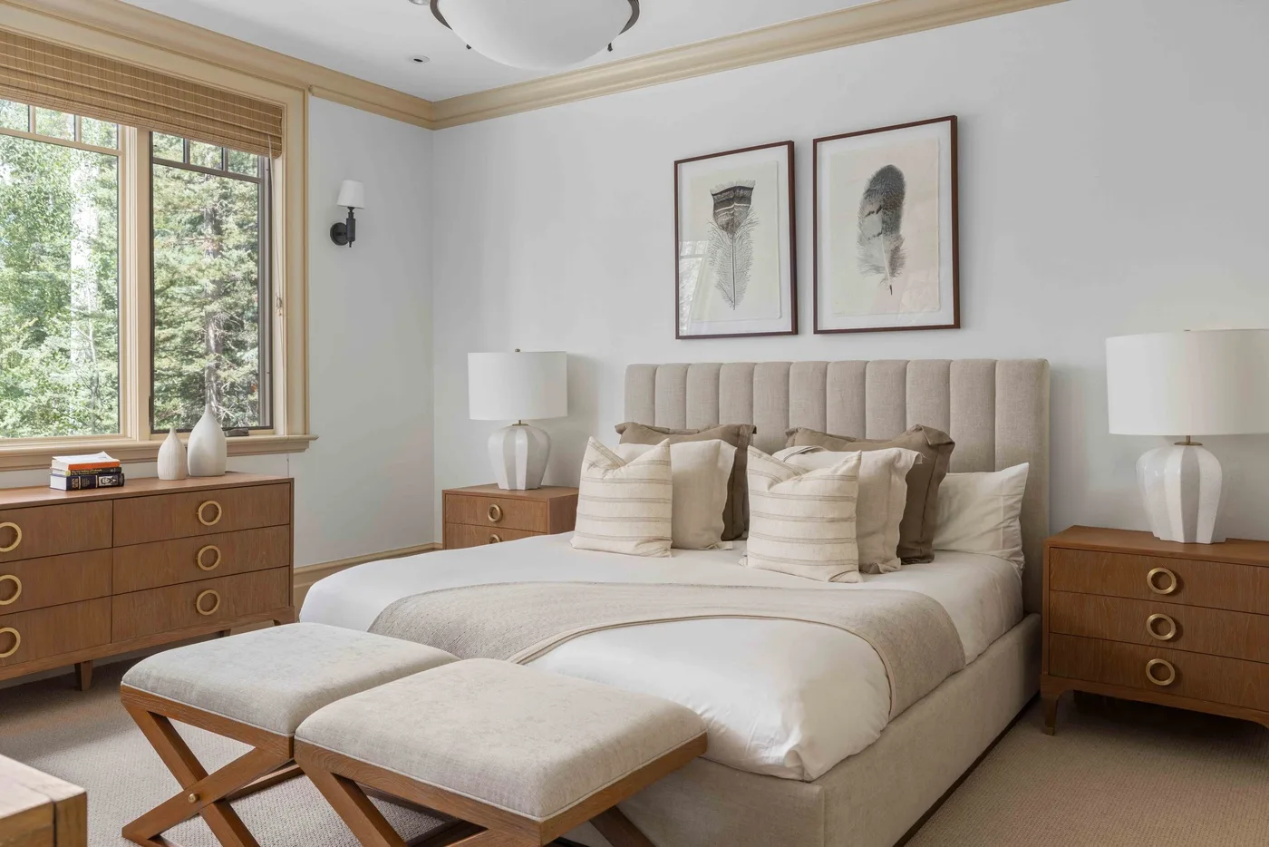 A bedroom with a bed, upholstered headboard, and framed artwork above it.