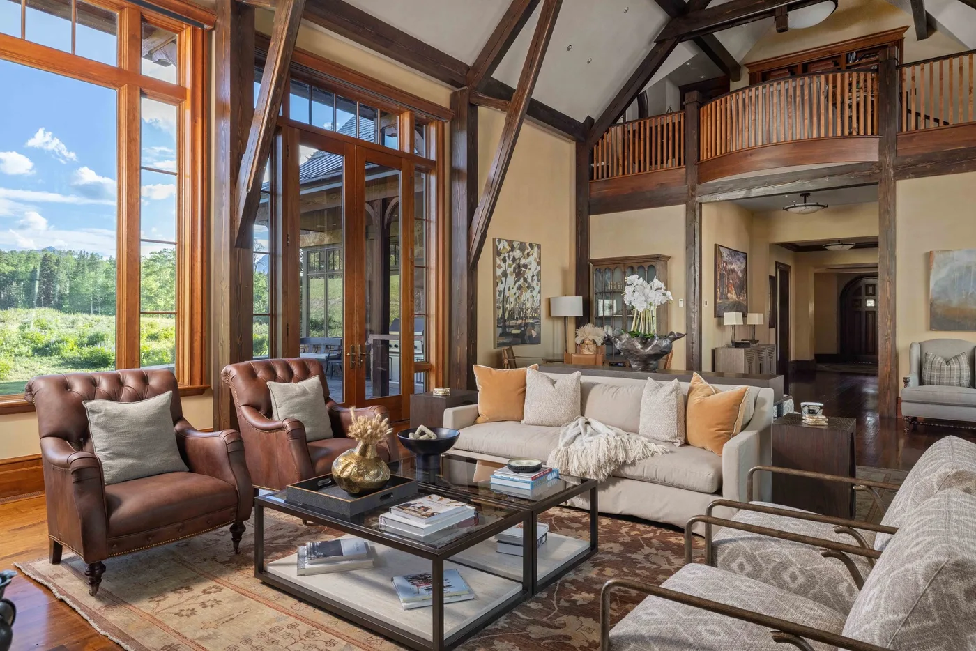 A spacious living room with seating, large windows, and an open timber ceiling.