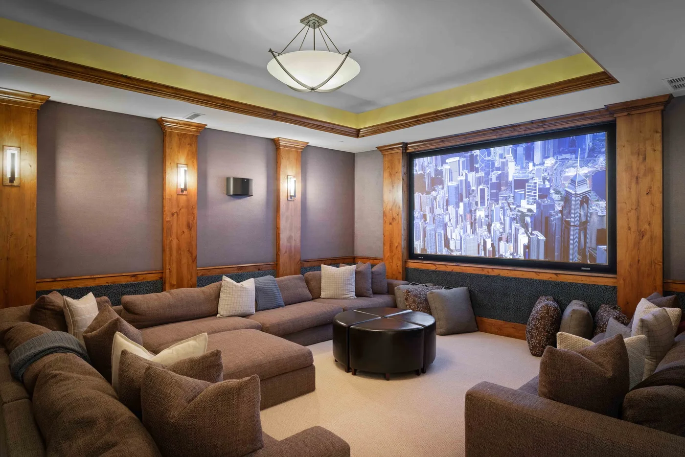 A lounge with sectional seating, a round coffee table, and a large city-view screen.