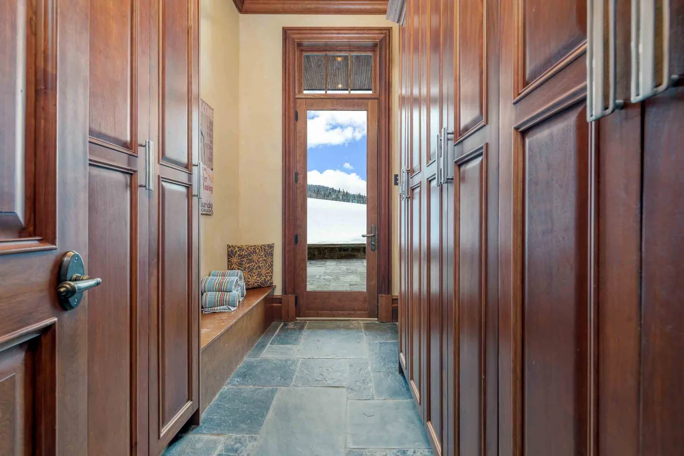 A wood-paneled hallway leads to a glass door overlooking a lake.