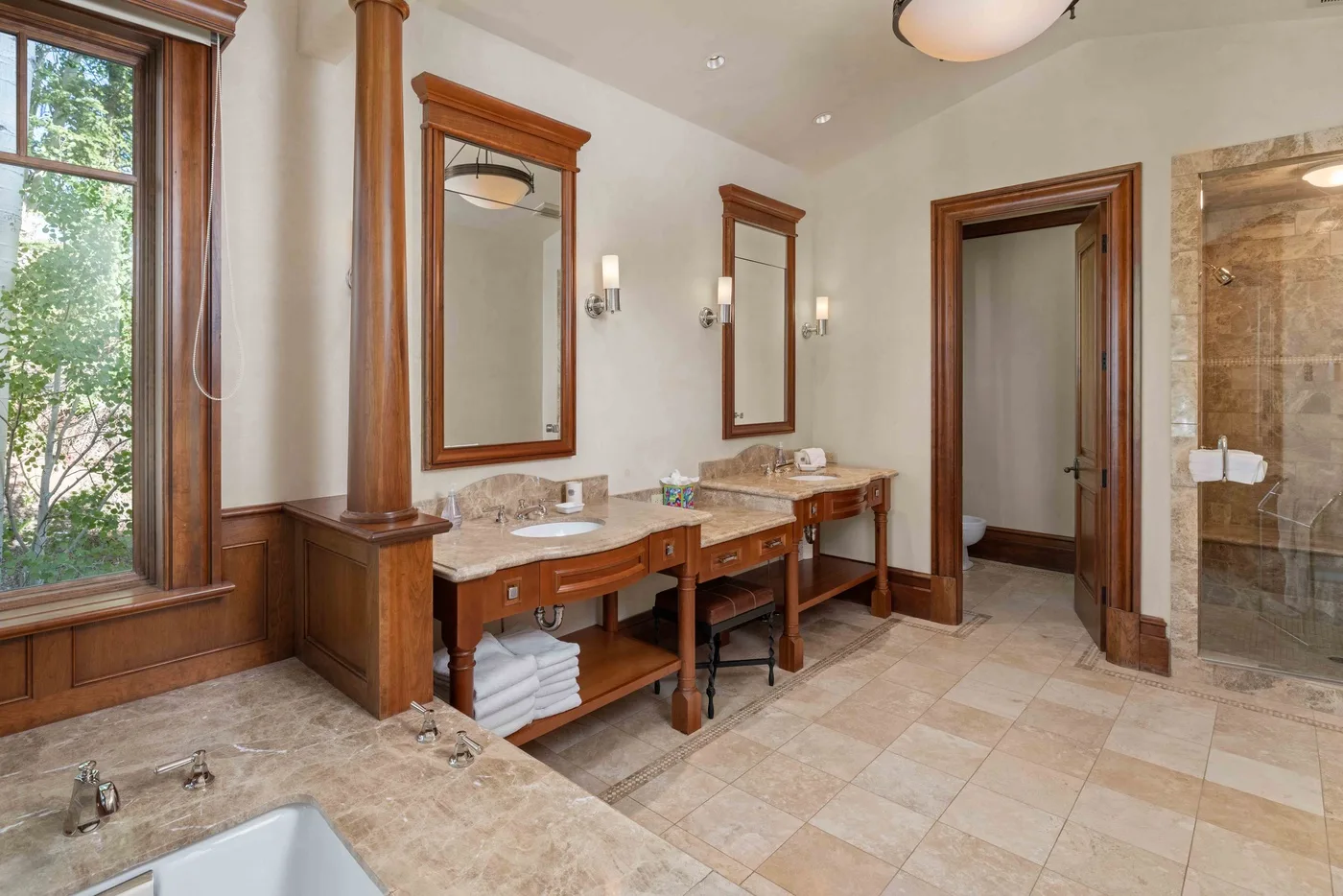 A spacious bathroom with wooden vanities, mirrors, and a glass shower.