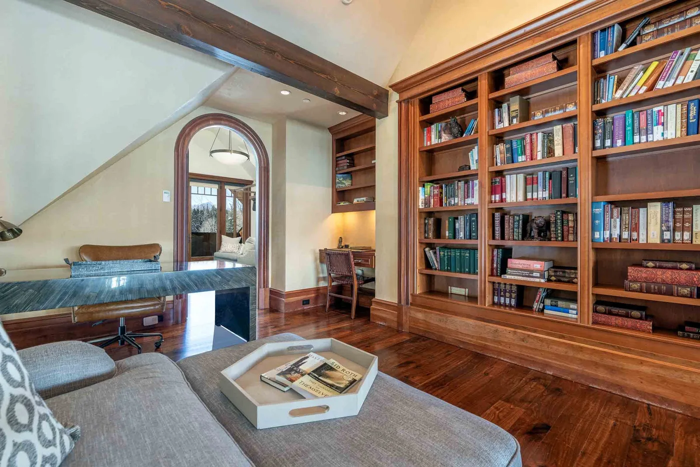 A cozy study with floor-to-ceiling bookshelves and a seating area.