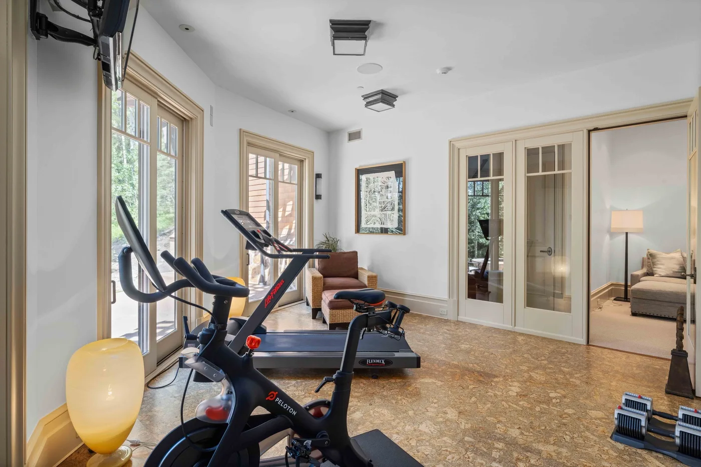 A bright exercise room with fitness equipment beside large windows.