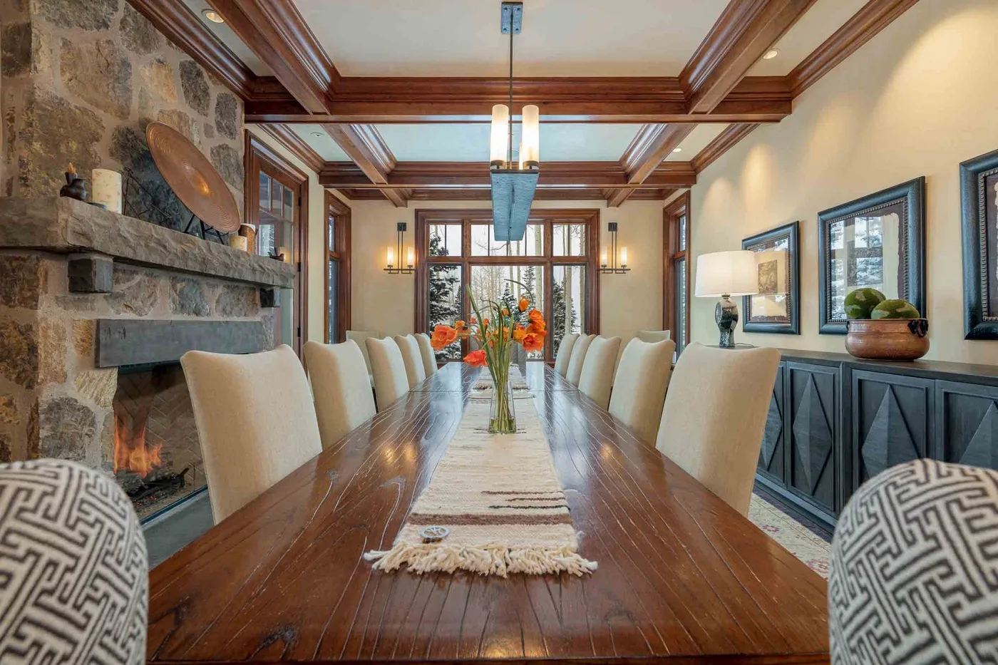 A formal dining room has a long wooden table beneath a coffered ceiling.