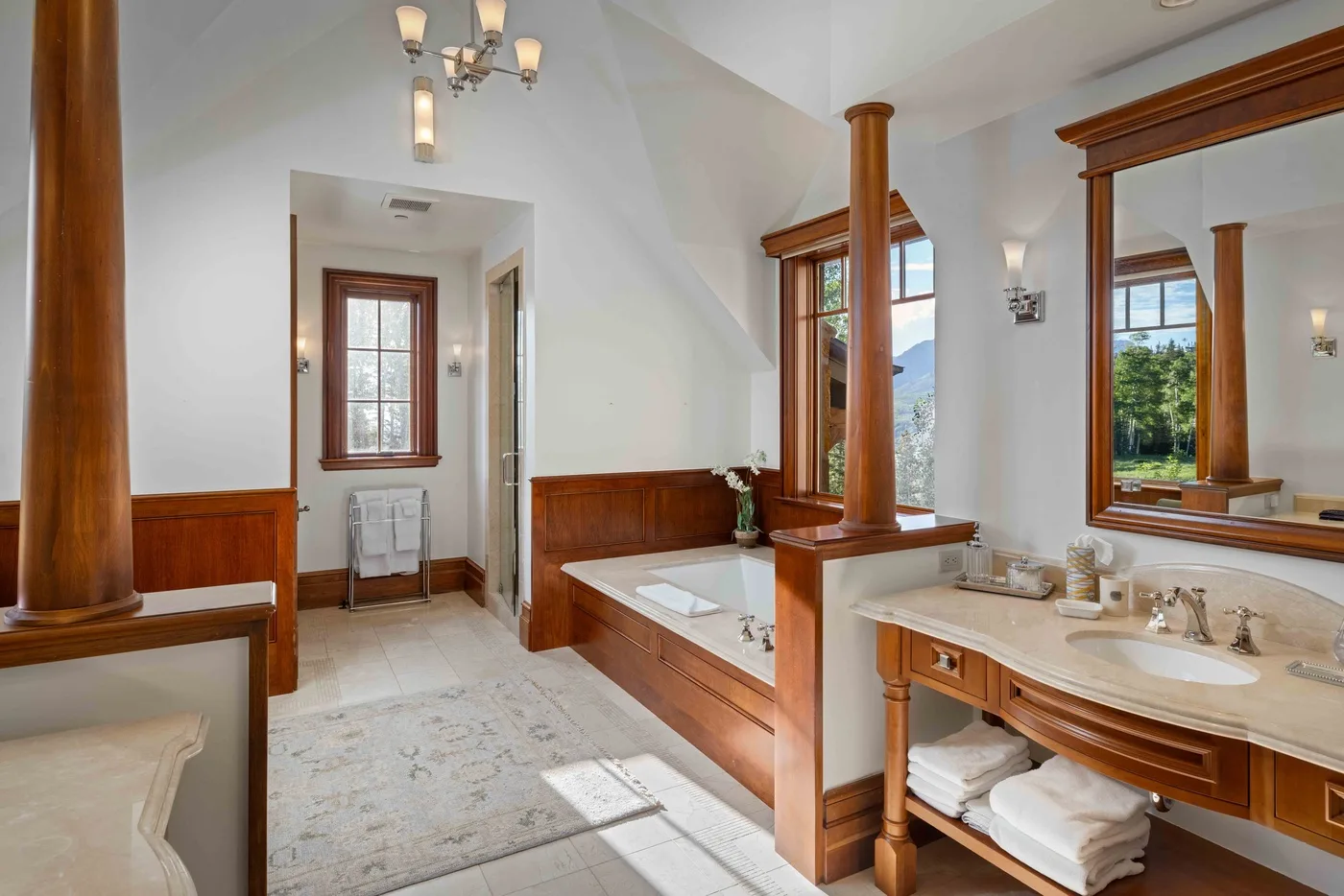 A bright bathroom with a built-in bathtub, wood trim, and a vanity.