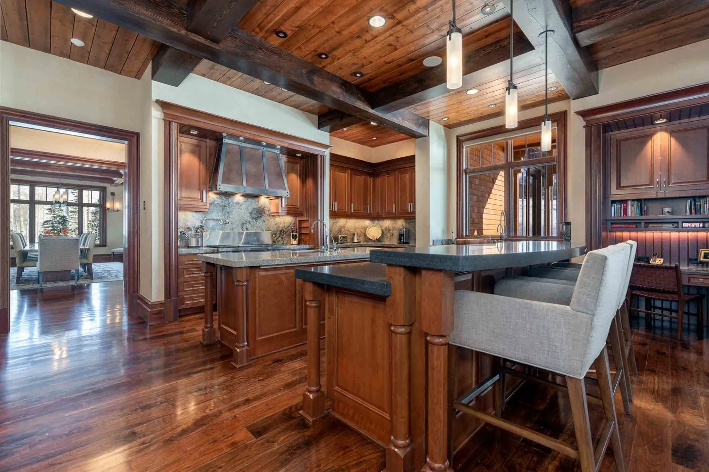 A kitchen with a large island, dark wood cabinetry, and pendant lights.