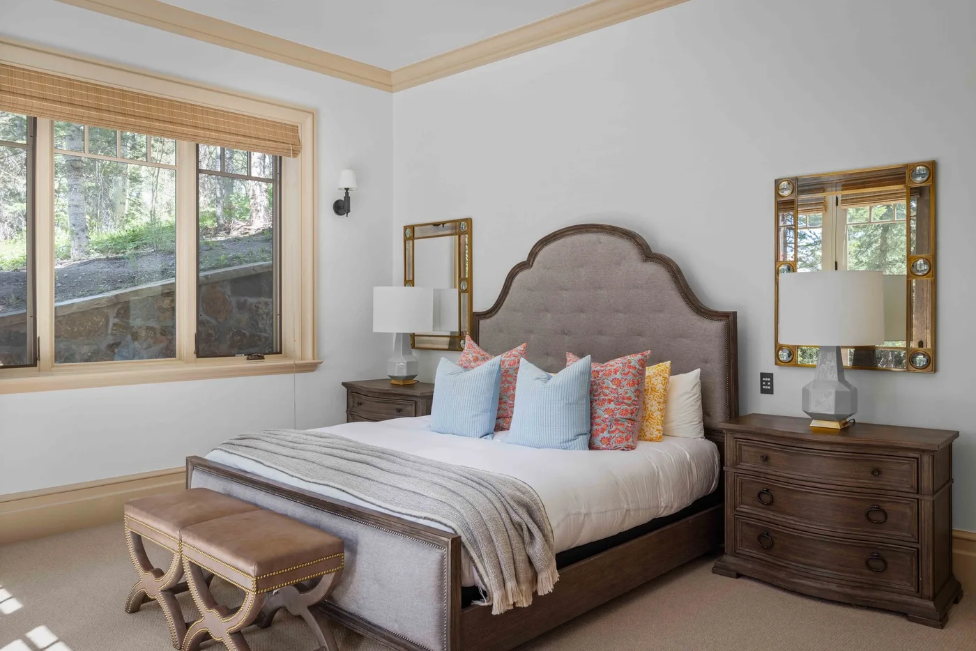 A bedroom with a bed, colorful pillows, and a large window.