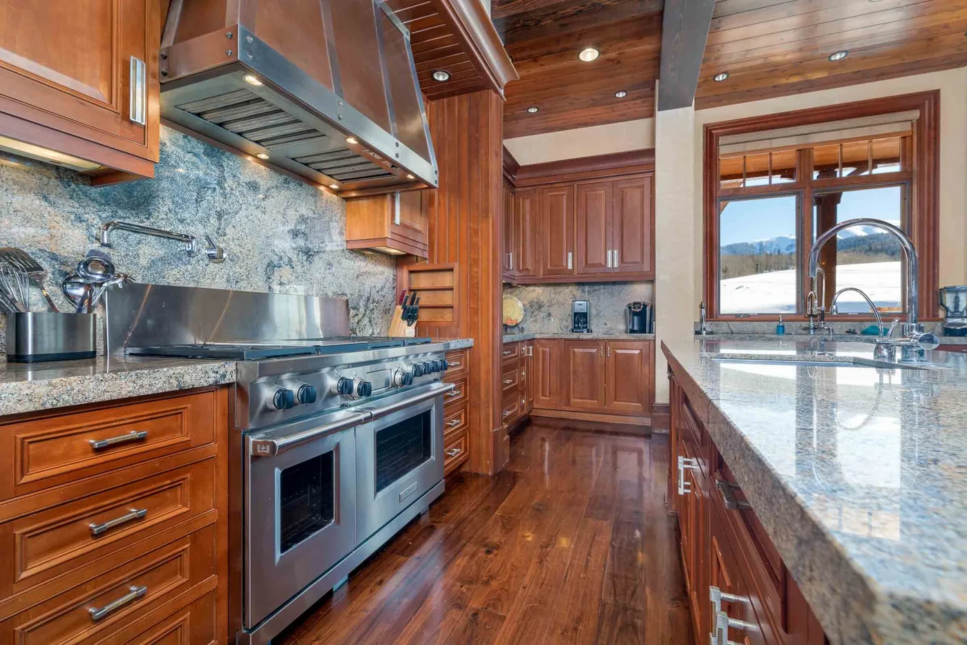 A wood-paneled kitchen with a large range and a bright window above the counter.