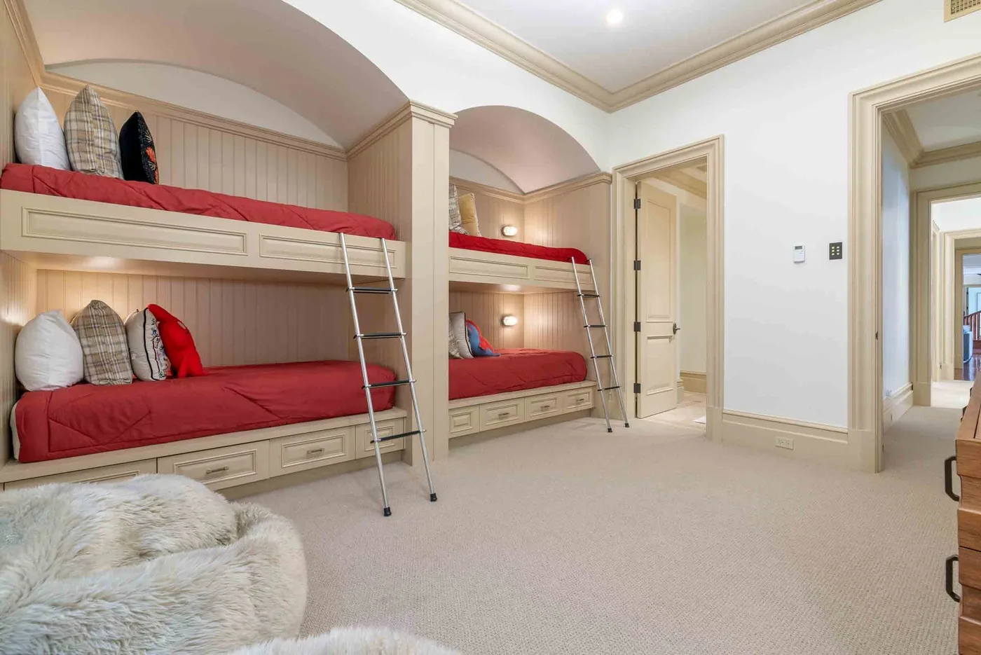 A bedroom with built-in bunk beds, red bedding, and a carpeted floor.