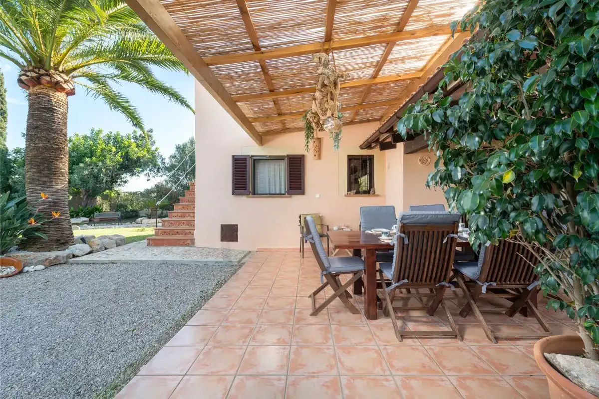 A tiled outdoor patio with dining seating sits beneath a shaded pergola.