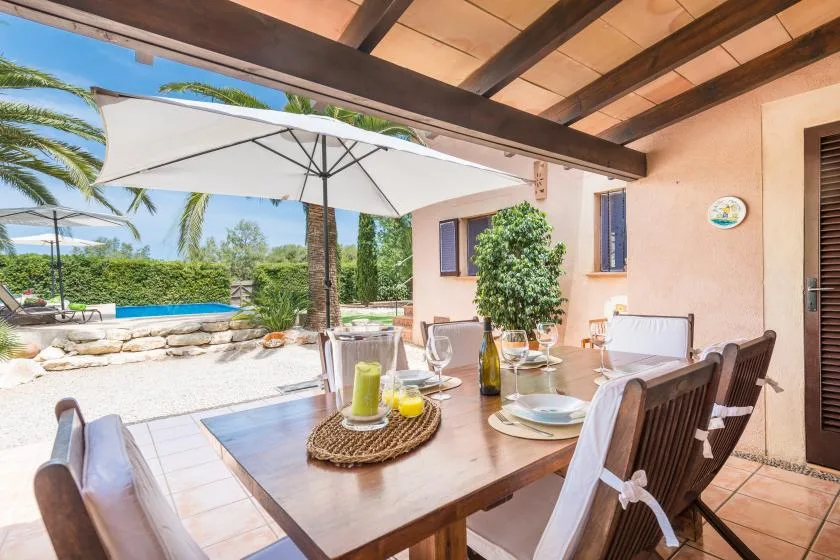 A covered outdoor dining area overlooks a pool and landscaped garden.