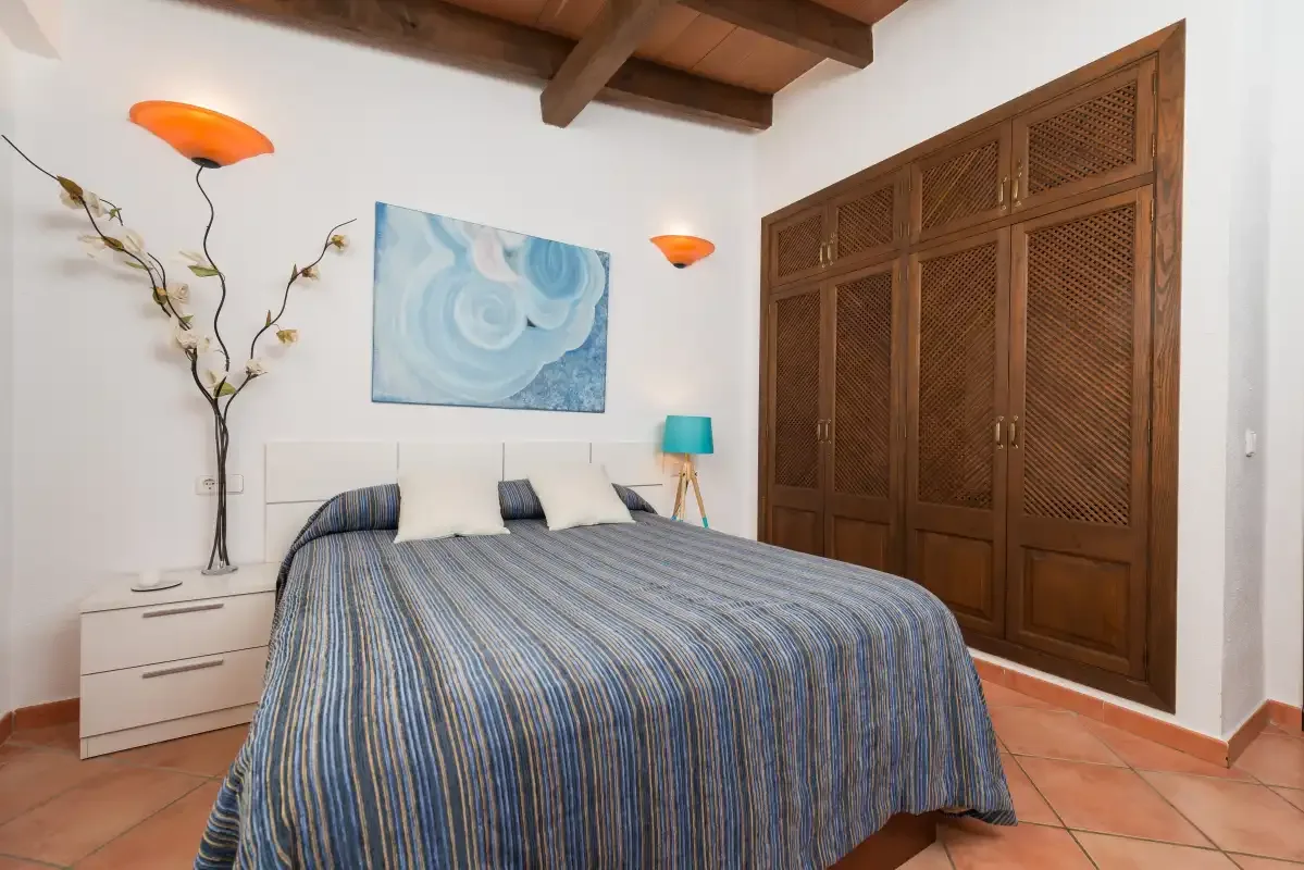 A bedroom with a bed, wall art, and wooden wardrobe doors.