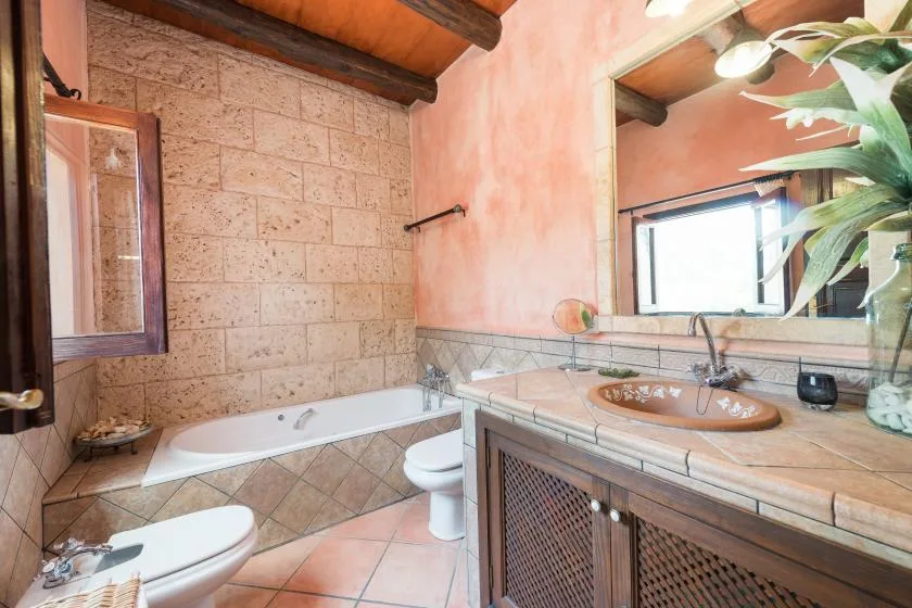 A bathroom with a bathtub, sink, and tiled surfaces.