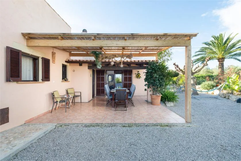 A covered patio with outdoor seating and a dining table beside a garden.