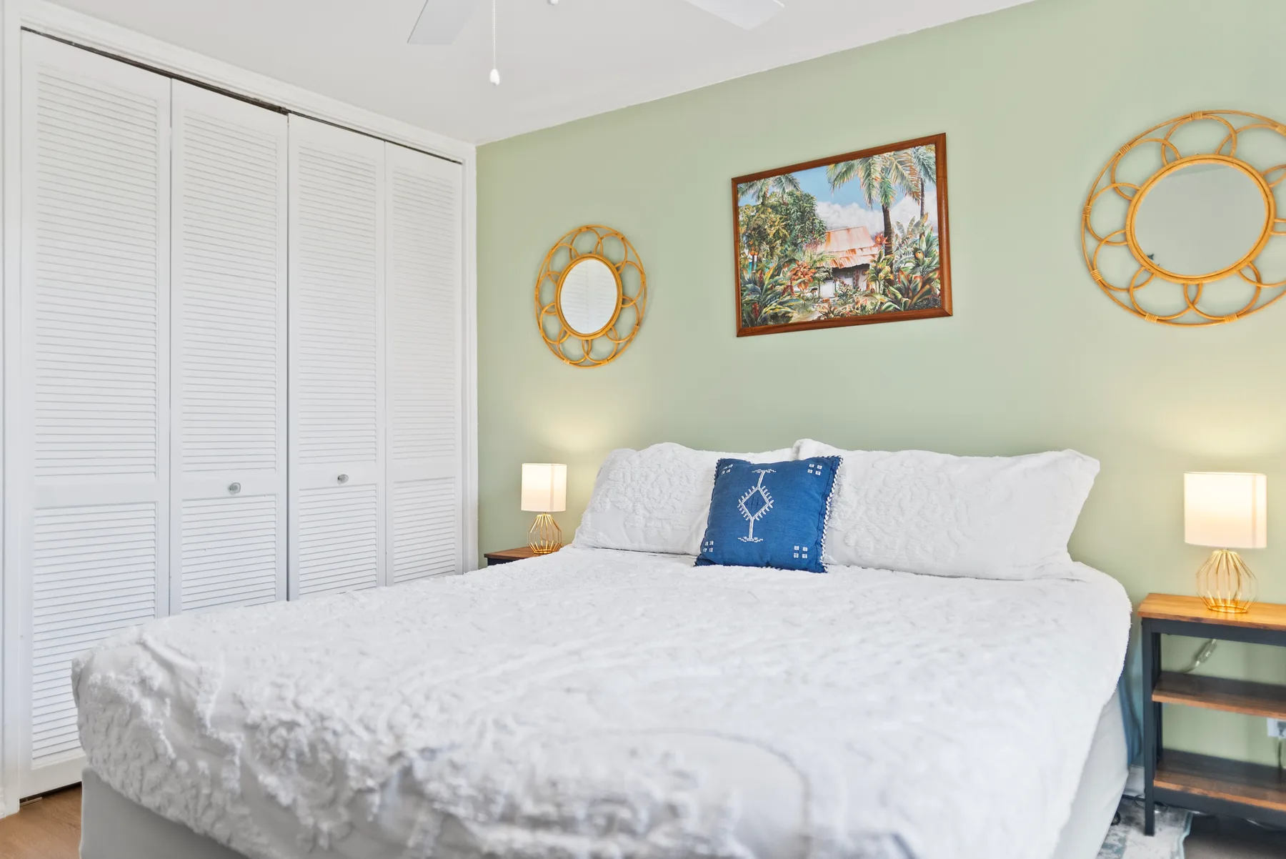 A bedroom with a white bed, framed artwork, and round wall mirrors.