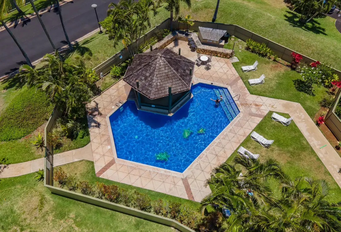 An aerial view of a swimming pool with a small pavilion and surrounding lawn.