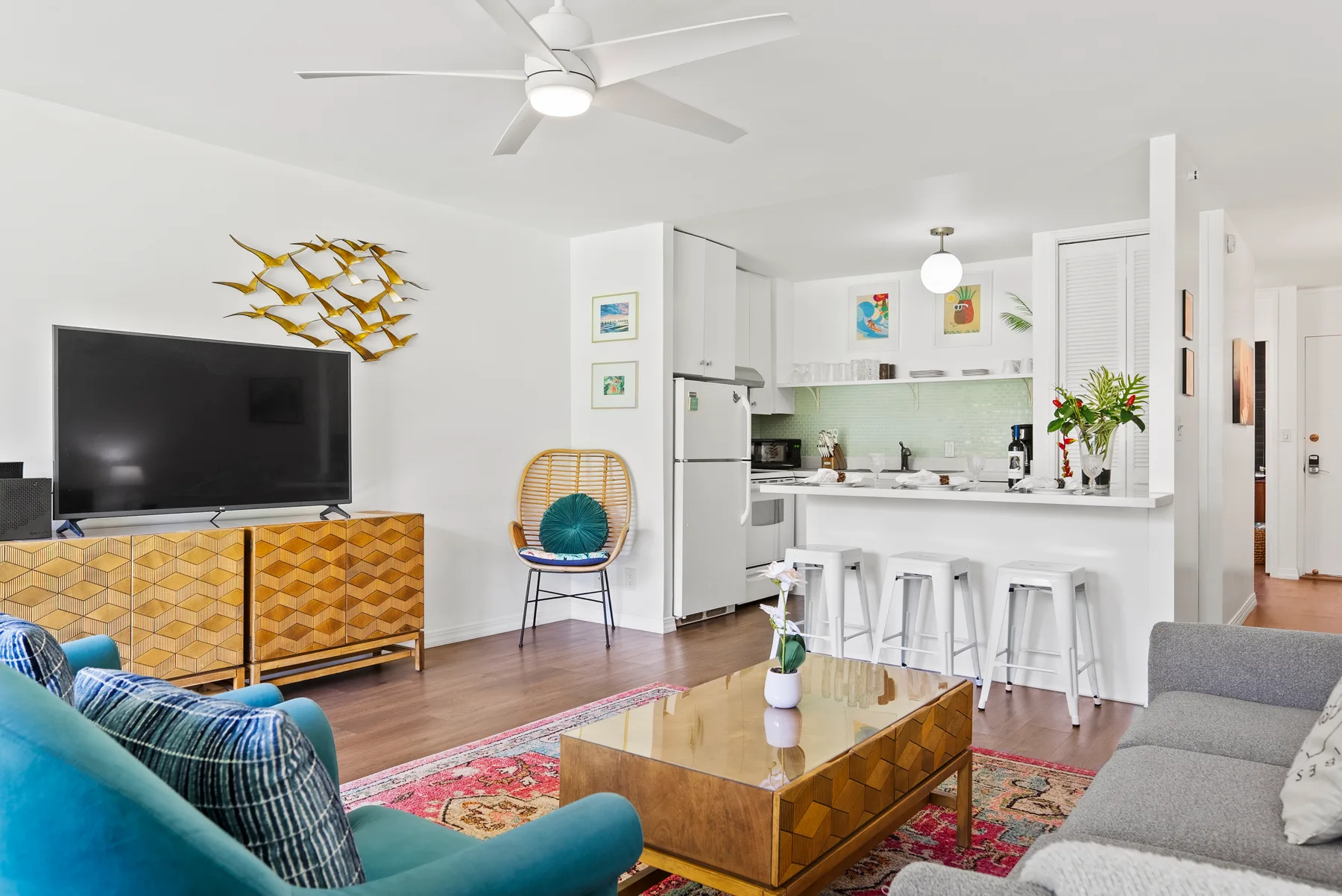 A bright living room opens onto a kitchen, with seating around a coffee table.