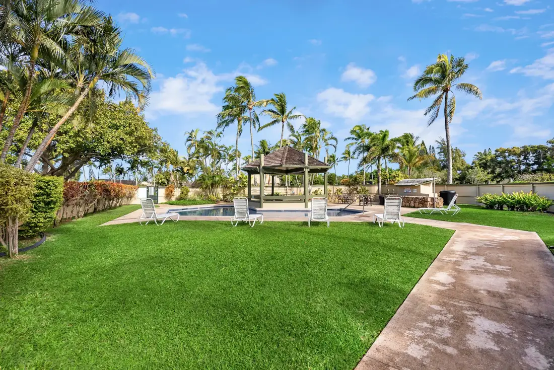 A landscaped outdoor pool area with a covered pavilion and palm trees.
