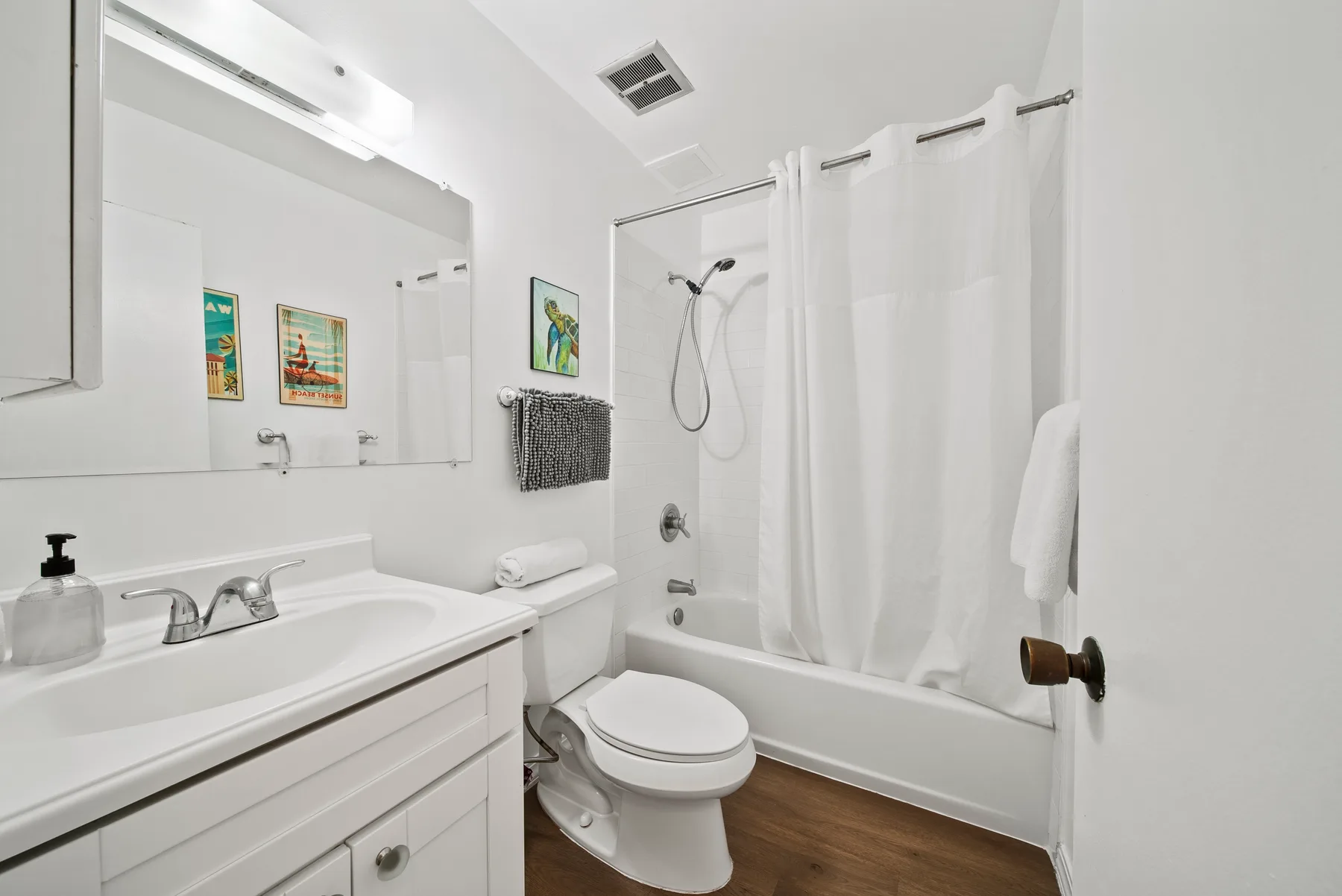 A bright bathroom with a bathtub, shower curtain, and sink.