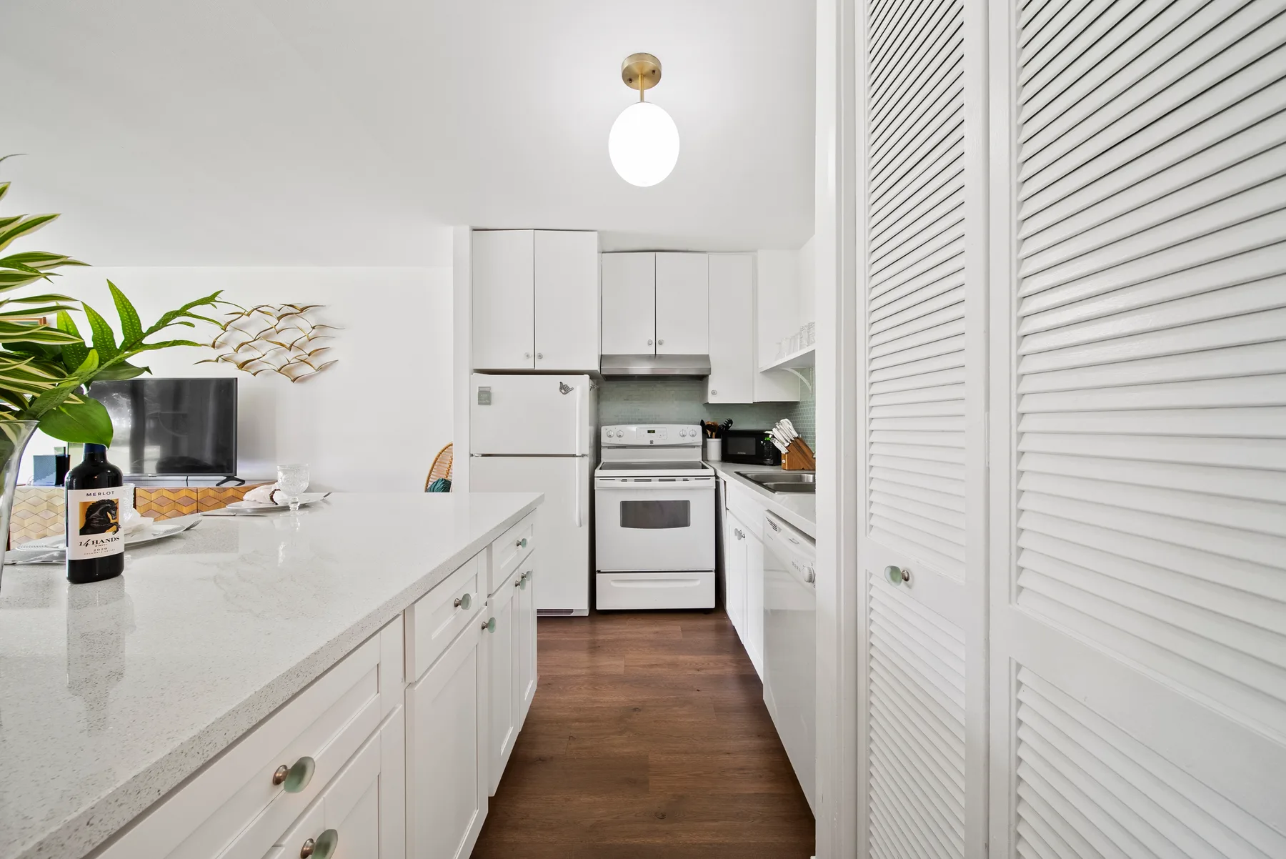 A bright kitchen with white cabinets, countertops, and cooking appliances.