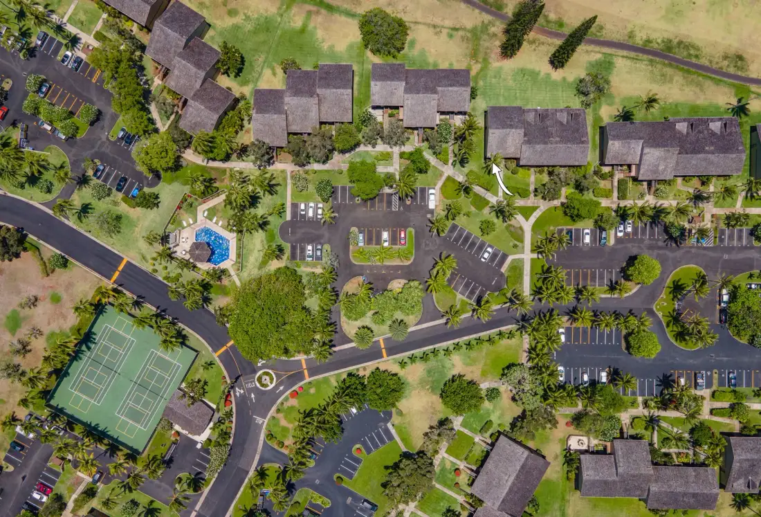An aerial view of a landscaped property with buildings, parking areas, and tennis courts.