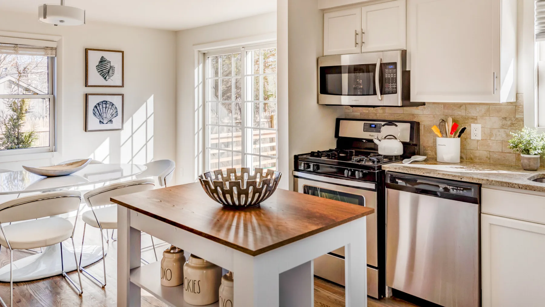 Una cocina luminosa con zona de comedor, isla y mesa de madera.