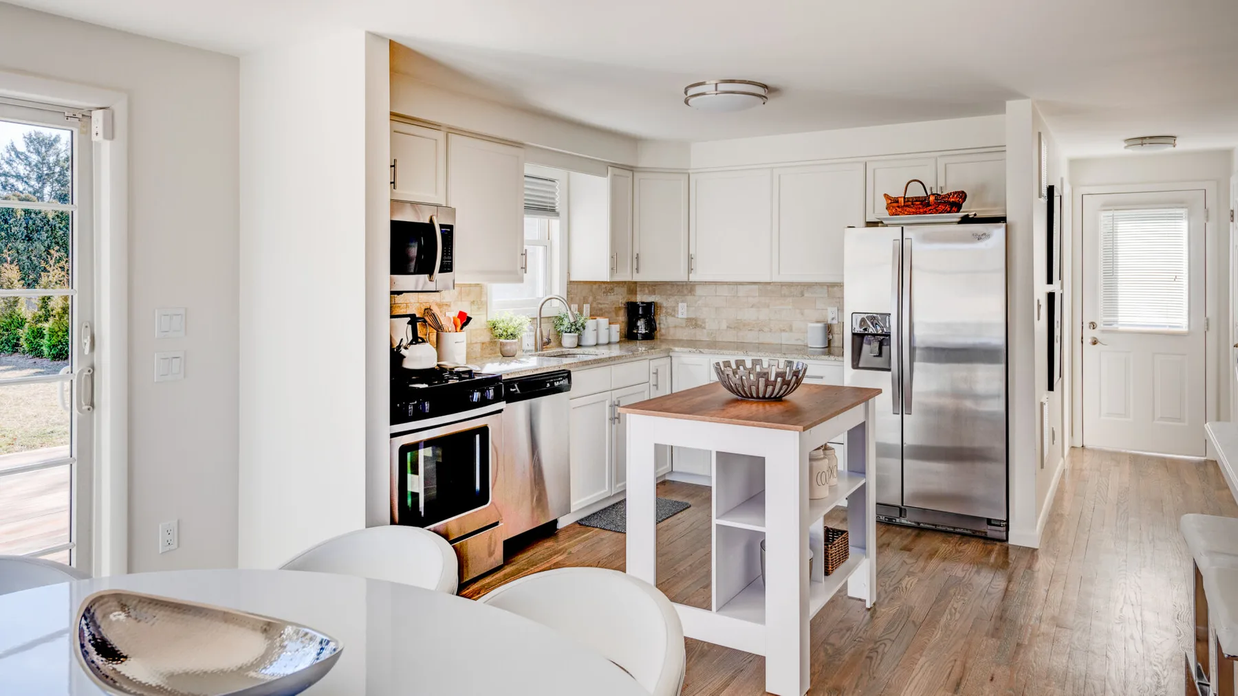Una cocina luminosa con gabinetes blancos y una isla central.