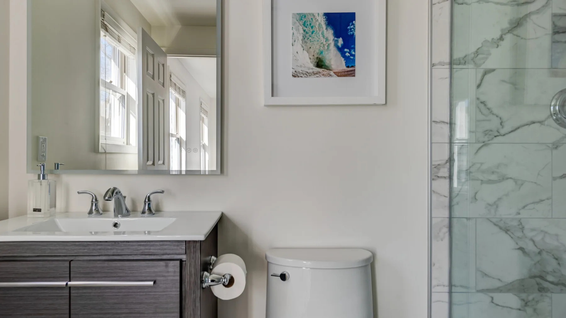 Un baño luminoso con lavabo, inodoro y ducha de cristal.